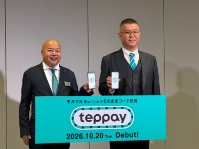 写真1：フォトセッションで、teppayの画面を表示したスマートフォンを持つJR東日本 執行役員 マーケティング戦略部 Suica・決済基盤構築ユニット長の牧野達朗氏（左）と、シソンヌの長谷川忍さん（右）